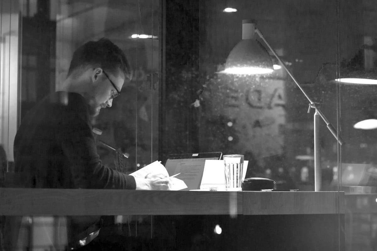 Mann sitzt nachts am Schreibtisch - Überstunden bei Kündigung - Rechtsanwalt für Arbeitsrecht Georg Gradl, Starnberg, ADVOLAW